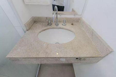 Apartamento à venda com 34m², 1 quarto e 1 vagaBanheiro com pia e vaso sanitário em granito e azulejos brancos.