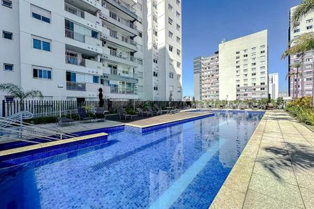 Apartamento à venda com 57m², 2 quartos e 1 vagaPiscina com decoração e mobília ao redor, vista para apartamentos e edifícios ao fundo.