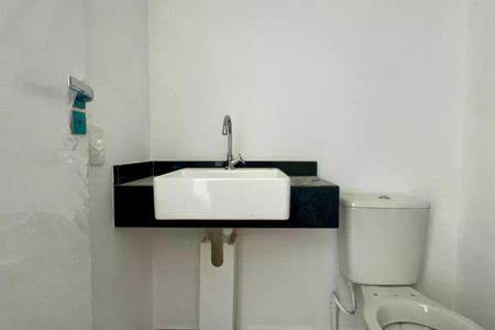 Apartamento à venda com 25m², 1 quarto e sem vagaBanheiro com pia e vaso sanitário brancos, com uma bancada de granito preta.