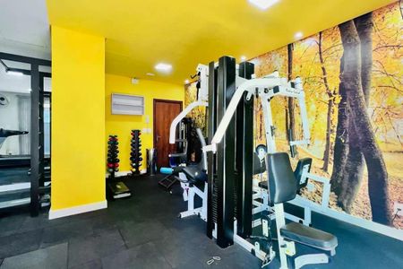 Apartamento à venda com 110m², 3 quartos e 2 vagas Apartamento à venda com 110m², 3 quartos e 2 vagasSala de ginástica com equipamentos de treino e parede com imagem de floresta.