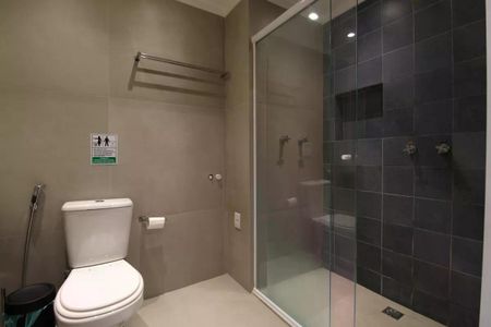 Banheiro com chuveiro e vaso sanitário, com piso de porcelanato e parede de azulejo. de apartamento à venda com 1 quarto, 26m² em Moema, São Paulo