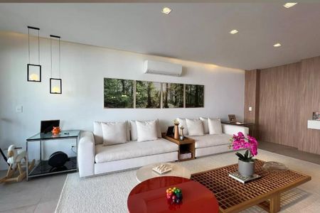 Apartamento à venda com 265m², 4 quartos e 3 vagasSala de estar com sofás brancos, mesas de centro e quadros de floresta na parede.