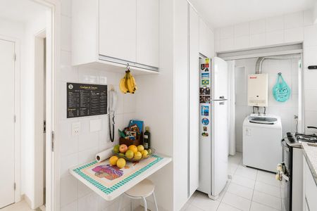 Apartamento à venda com 93m², 4 quartos e 2 vagasCozinha com móveis brancos e iluminação natural, com uma mesa de madeira e uma geladeira branca.