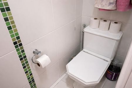 Apartamento à venda com 70m², 2 quartos e 1 vagaBanheiro com piso de azulejos, vaso sanitário e papel higiênico, com uma garrafa de limpeza ao lado do vaso.