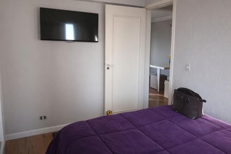 Apartamento à venda com 70m², 2 quartos e 1 vagaQuarto com cama de casal, TV e porta fechada, com um saco de viagem no canto.
