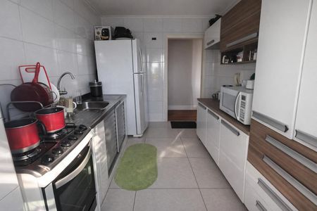 Apartamento à venda com 70m², 2 quartos e 1 vagaCozinha com geladeira, fogão e pia, com móveis de madeira e azulejos brancos.