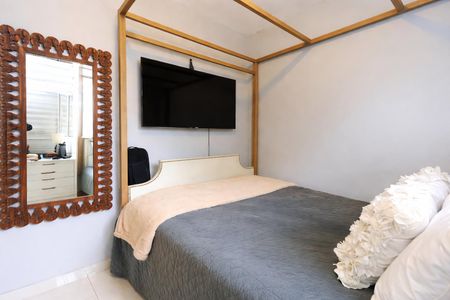 Cama com colchão e travesseiro branco, com uma TV montada na parede acima da cama, com uma porta de vidro e uma janela ao lado da porta. de apartamento à venda com 2 quartos, 48m² em Morumbi, São Paulo