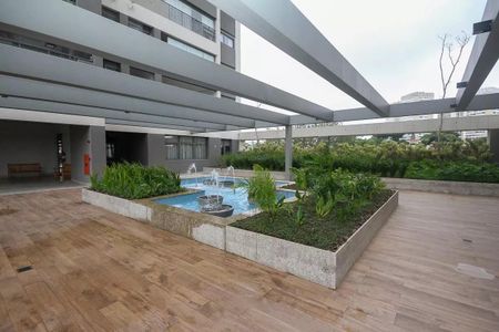 Apartamento à venda com 121m², 6 quartos e 2 vagasPiscina com fonte de água e jardim em frente a um prédio residencial.