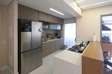Apartamento à venda com 121m², 6 quartos e 2 vagasCozinha moderna com geladeira, fog. O e pia de vidro, iluminada por luzes brancas e com acabamento em madeira e azulejos.