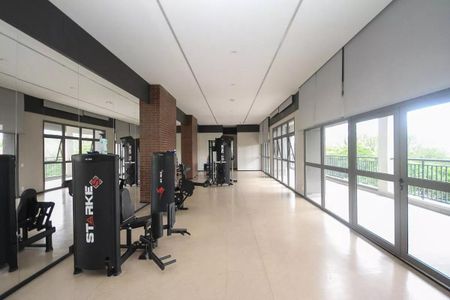 Apartamento à venda com 121m², 6 quartos e 2 vagasSala de ginástica com equipamentos de treino e janelas grandes, oferecendo uma vista para a cidade.