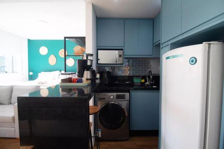 Cozinha com móveis azuis e brancos, com uma geladeira, fogão e máquina de lavar roupa. de kitnet/studio à venda com 1 quarto, 31m² em Pinheiros, São Paulo