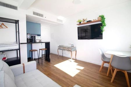 Sala de estar com sofá, mesa e TV, iluminada por luz natural e com vista para a cidade. de kitnet/studio à venda com 1 quarto, 31m² em Pinheiros, São Paulo