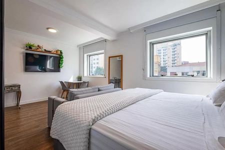 Quarto com cama de casal, TV e sofá, com vista para a cidade. de kitnet/studio à venda com 1 quarto, 31m² em Pinheiros, São Paulo