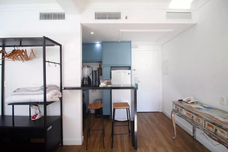 Quarto com cama, mesa e cadeira, e uma pequena cozinha com geladeira e fogão. de kitnet/studio à venda com 1 quarto, 31m² em Pinheiros, São Paulo