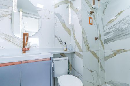 Apartamento à venda com 135m², 3 quartos e 3 vagas Apartamento à venda com 135m², 3 quartos e 3 vagasBanheiro com piso de porcelanato, pia e vaso sanitário brancos, e espelho redondo com iluminação de LED.