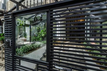 Apartamento à venda com 105m², 3 quartos e 1 vagaPraça de entrada com portão de ferro e janelas com números 64, com plantas ao lado e uma câmera de segurança.