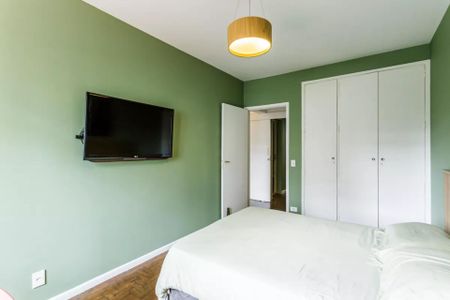 Apartamento à venda com 105m², 3 quartos e 1 vagaQuarto com cama e TV montada na parede, com porta de acesso ao banheiro.