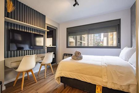 Quarto com cama de casal, TV e mesa de trabalho, com vista para a cidade. de kitnet/studio à venda com 1 quarto, 26m² em Pinheiros, São Paulo