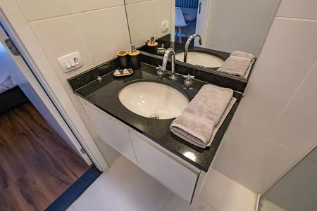 Banheiro com pia e vaso sanitário, com toalhas e acessórios de higiene. de kitnet/studio à venda com 1 quarto, 26m² em Pinheiros, São Paulo