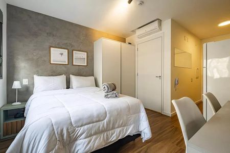 Quarto simples com cama de casal e móveis brancos, com uma parede de concreto e uma porta de madeira. de kitnet/studio à venda com 1 quarto, 26m² em Pinheiros, São Paulo