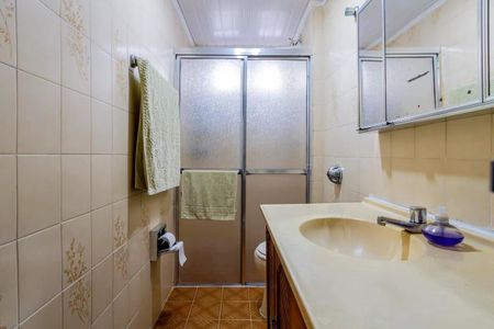 Apartamento à venda com 84m², 3 quartos e 2 vagasBanheiro com piso de azulejos, pia de porcelana e espelho de madeira.