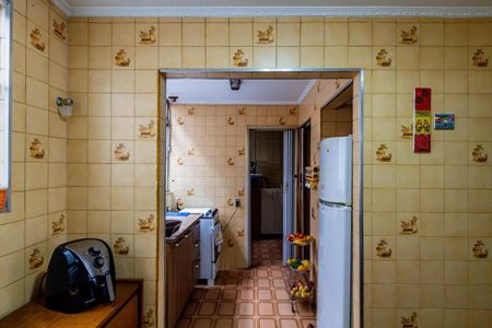 Apartamento à venda com 84m², 3 quartos e 2 vagasCozinha com geladeira, fogão e forno, com móveis de madeira e azulejos amarelos e brancos.