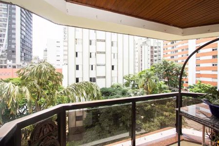Apartamento à venda com 195m², 4 quartos e 3 vagasVaranda com vista para o jardim e edifícios ao fundo, com móveis e plantas, em um dia ensolarado.