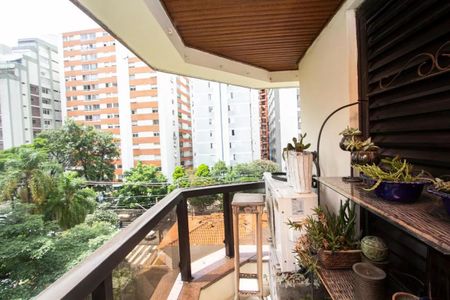 Apartamento à venda com 195m², 4 quartos e 3 vagasVaranda com vista para o jardim e edifícios ao fundo, com móveis e plantas.