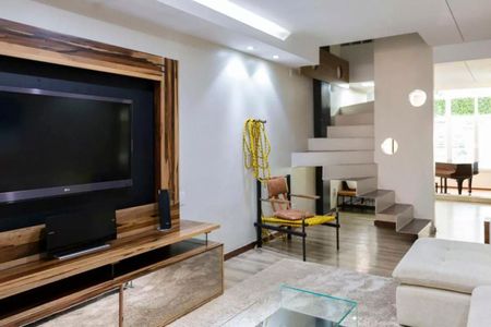Sala de estar com TV e sofá em madeira, com uma escada de metal e vidro no fundo. de casa à venda com 6 quartos, 280m² em Cerqueira César, São Paulo