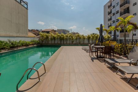Apartamento à venda com 46m², 2 quartos e 1 vagaPiscina com deck e vista para a cidade, com cadeiras e mesas ao redor.