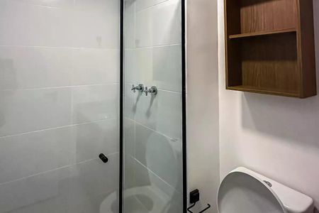 Apartamento à venda com 50m², 2 quartos e 1 vagaBanheiro com chuveiro e pia branca, paredes brancas e teto branco, com uma prateleira de madeira acima do vaso sanitário.
