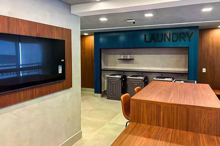 Apartamento à venda com 50m², 2 quartos e 1 vagaSalão de lavanderia comum, com bancos e televisão, em apartamento de luxo.
