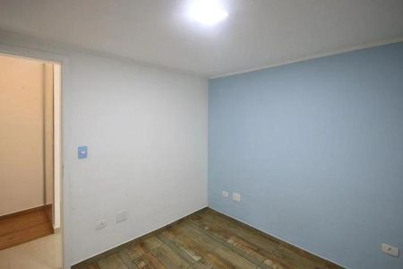 Casa à venda com 150m², 2 quartos e 1 vagaQuarto com piso de madeira e parede azul, iluminado por uma lâmpada de teto.