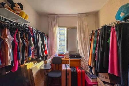 Apartamento à venda com 96m², 4 quartos e 2 vagas Apartamento à venda com 96m², 4 quartos e 2 vagasQuarto pequeno com muitos objetos e roupas, com uma janela e uma mesa com computador.