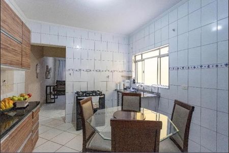 Cozinha com móveis de madeira e piso de porcelanato, com uma mesa de vidro e quatro cadeiras de madeira. de casa à venda com 3 quartos, 160m² em Casa Grande, Diadema