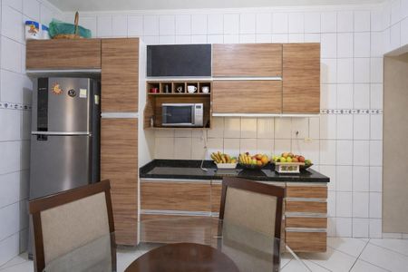 Casa à venda com 160m², 3 quartos e 2 vagasCozinha com móveis de madeira, geladeira, micro-ondas e frutas no balcão.