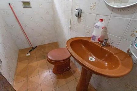 Casa à venda com 160m², 3 quartos e 2 vagasBanheiro com pia e vaso sanitário em tons de laranja, com piso de azulejo e parede de azulejo branco.
