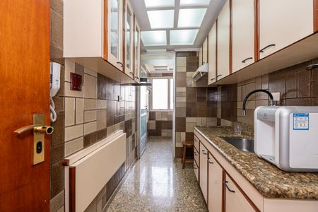 Apartamento à venda com 106m², 2 quartos e 2 vagas Apartamento à venda com 106m², 2 quartos e 2 vagasCozinha com móveis de madeira e azulejos em tons de marrom e creme, com iluminação natural através de uma janela grande e uma luminária acima da pia.