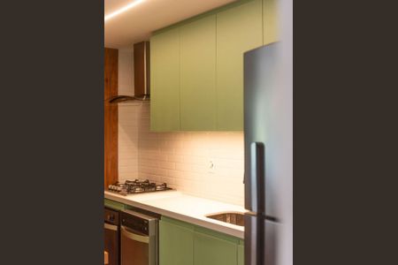 Cozinha com gavetas de cor verde e piso de porcelanato branco, com fogão e geladeira de aço inox. de apartamento para alugar com 2 quartos, 84m² em Leblon, Rio de Janeiro