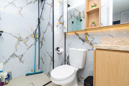 Banheiro com piso de porcelanato, bancada de granito e móveis de madeira, com uma pia e um vaso sanitário. de kitnet/studio à venda com 0 quarto, 24m² em Pompeia, São Paulo