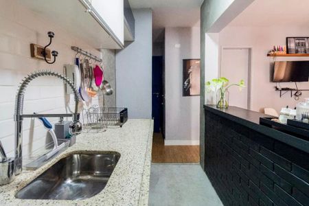 Apartamento à venda com 35m², 2 quartos e 1 vagaCozinha com pia e fog. o, com utens.rios pendurados na parede, e uma porta para a sala de estar.