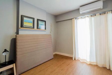 Cama com cabeceira de tecido e pintura de quadros em tons de azul e amarelo. de apartamento à venda com 2 quartos, 35m² em Jardim Paulista, São Paulo