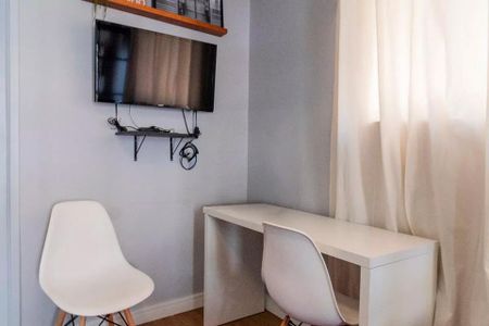 Sala de trabalho com mesa e cadeiras brancas, TV e prateleira de madeira, parede azul e janela com cortina branca. de apartamento à venda com 2 quartos, 35m² em Jardim Paulista, São Paulo