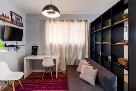 Sala de estar com sofá e mesa de trabalho, iluminação natural e decoração simples. de apartamento à venda com 2 quartos, 35m² em Jardim Paulista, São Paulo