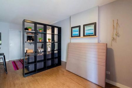 Cama de cama com cabeceira e prateleira de livros e plantas no quarto. de apartamento à venda com 2 quartos, 35m² em Jardim Paulista, São Paulo