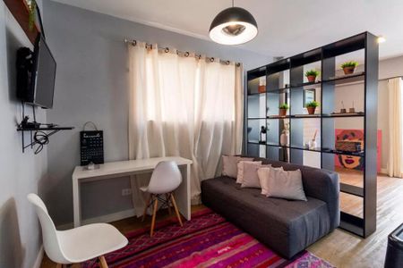 Sala de estar com sofá e mesa de trabalho, iluminação natural e decoração simples. de apartamento à venda com 2 quartos, 35m² em Jardim Paulista, São Paulo