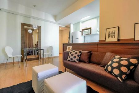 Sala de estar com sofá, mesas e cadeiras, iluminada por lâmpadas e com uma vista para a cidade. de apartamento à venda com 2 quartos, 51m² em Cerqueira César, São Paulo