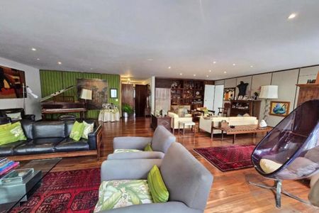 Apartamento à venda com 370m², 6 quartos e 3 vagas Apartamento à venda com 370m², 6 quartos e 3 vagasSala de estar com móveis de madeira e tapetes coloridos, com uma grande pintura na parede e um piano no fundo.