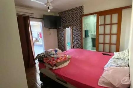 Casa à venda com 92m², 3 quartos e 2 vagas Casa à venda com 92m², 3 quartos e 2 vagasCama com colchão vermelho e cobertor branco, com uma televisão na parede e uma porta de vidro para o exterior.