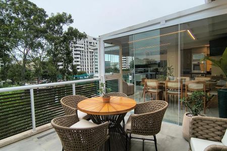 Apartamento à venda com 150m², 5 quartos e 2 vagas Apartamento à venda com 150m², 5 quartos e 2 vagasVaranda com vista para a cidade, com mesa e cadeiras de madeira e móveis de wicker, com jardim e árvores ao fundo.